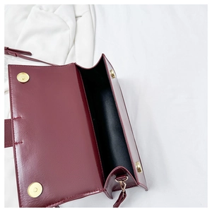 Detailed view of the dark red leather baguette bag interior and golden magnetic buckles