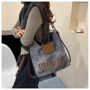 Detail showing high-capacity blue denim tote bag with leather strap on a model shoulder