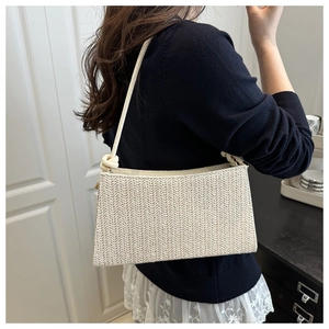 Detalle del bolso tote de paja crema con textura suave y nudos decorativos en la correa