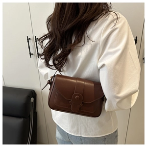 Close-up of a brown vintage style shoulder bag with a unique round decorative buckle detail