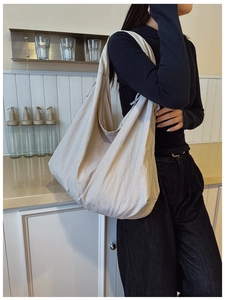Detail of large beige hobo shoulder bag featuring soft pleated nylon texture and casual style