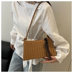 Detalle de bolso tote de paja tejida con textura marrón y cordón decorativo bicolor