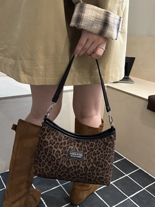 Chic leopard print tote bag with black leather trim and silver hooks held by a model