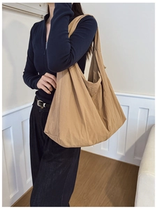 Close-up of khaki nylon tote bag showing soft pleated texture and wide shoulder strap