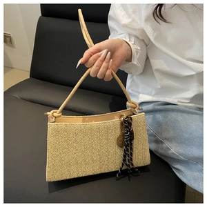 Detalle de bolso tipo tote de paja con tejido de espiga y colgante de raqueta de tenis