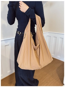 Detail of khaki large capacity tote bag with nylon texture and side zipper on a shoulder