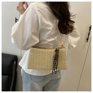 Detail of woven straw shoulder bag in beige with black and white scarf and leather strap