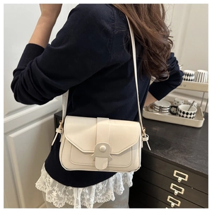 Gros plan du sac bandoulière ivoire avec boucle demi-ronde et coutures fines