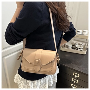 Detail view of a beige PU leather crossbody bag worn with a casual navy blue sweater