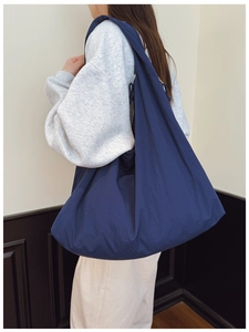 Detailed side view of dark blue large nylon tote bag showing textured fabric and wide strap