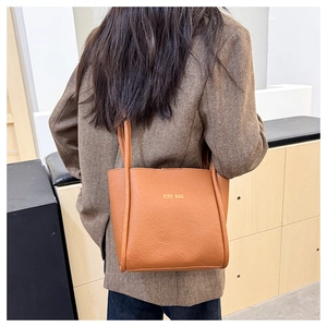 Close-up of caramel lychee grain leather tote bag with elegant gold lettering detail