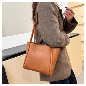 Close-up of brown pebbled leather tote bag worn with a brown herringbone wool blazer