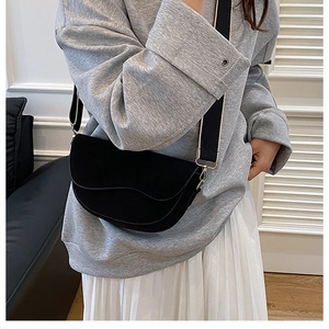 Close-up of black matte saddle bag featuring a wide black and white woven shoulder strap