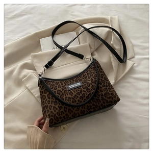 Close-up of leopard print tote bag with black leather straps and adjustable shoulder belt