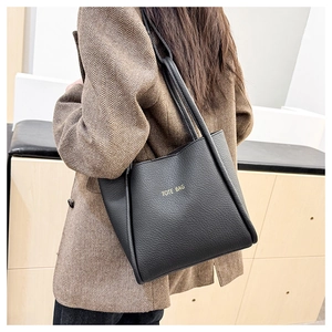 Schulteransicht einer schwarzen Tragetasche aus strukturiertem Leder mit Goldaufschrift