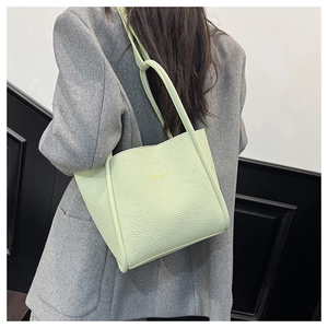 Detail of light green litchi texture tote bag with golden text on shoulder