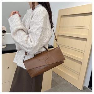 Detail showing the brown faux leather texture and embossed crocodile pattern on the handbag