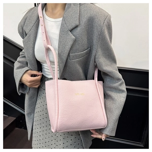 Detail der rosafarbenen Handtasche aus Kunstleder mit Narbung und goldenem Logo am Model