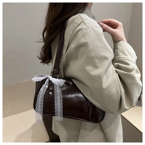 Détail du sac baguette marron foncé avec un grand nœud en dentelle blanche de style coquette