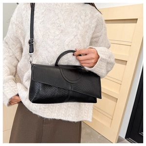 Detail of black crocodile texture handbag with silver hardware and detachable strap