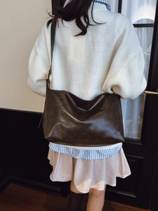 Minimalist large brown tote bag with adjustable strap worn by model in elegant casual outfit