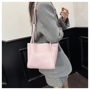 Detail of pink pebbled leather bucket bag featuring gold Tofu Bag lettering and thin strap