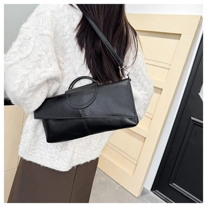 Detail of black faux leather bag featuring snake skin texture and metal circular buckle