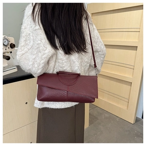 Detail of burgundy crocodile embossed handbag styled with a winter knit sweater
