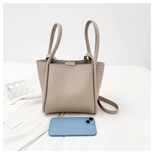 Detail of taupe pebbled leather tote bag with gold lettering beside a smartphone
