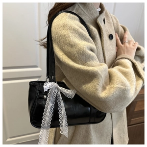 Vue détaillée du sac à bandoulière en cuir brillant noir avec nœud en dentelle