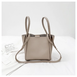 Macro shot of minimalist taupe bucket bag showing premium lychee grain leather texture