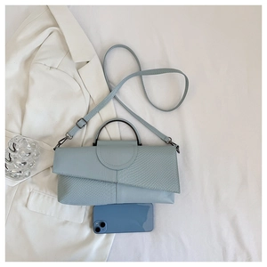 Detail of light blue faux crocodile skin crossbody bag showing size comparison with a phone