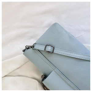 Detail of light blue crocodile texture leather handbag with dark metal hardware and fine stitching