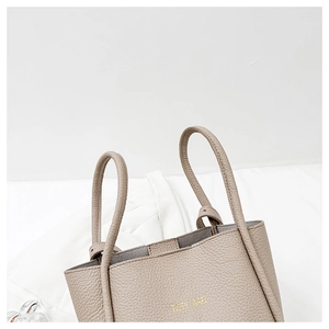 Detail of lychee pattern leather and gold TOTE BAG text on a beige fashionable handbag