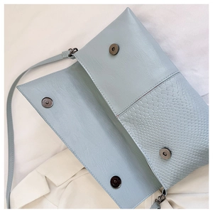 Detail view of light blue embossed crocodile texture flap handbag with four magnetic buckles
