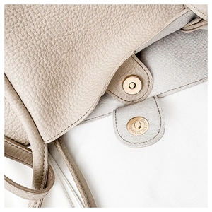 Detail of light beige pebble leather texture with double magnetic snap button closure