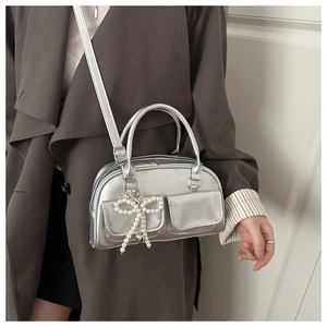 Detail of silver metallic handbag with dual front pockets and pearl bow charm