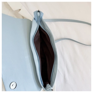 Detail view of light blue crocodile texture handbag with zipper and brown lining interior