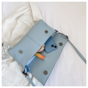 Internal view of light blue crocodile texture bag holding phone and cosmetics