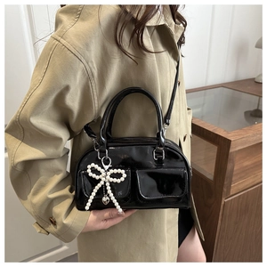 Detail of black patent leather bag with pearl bow charm and cargo style pockets