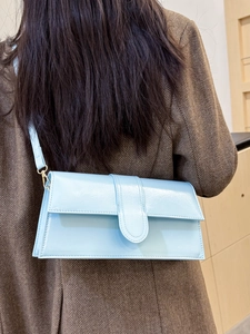 Light blue patent leather baguette bag worn over the shoulder with a stylish brown blazer