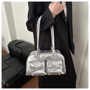 Silver PU leather bag featuring chic bow details and dual front pockets in detail