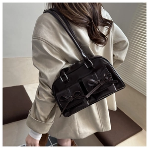 Detail of coffee PU leather shoulder bag with bow ties and metallic buckles on model