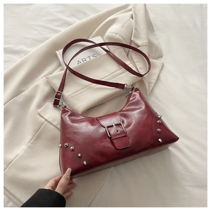 Detail of deep red retro shell bag featuring silver buckles and metallic rivets on faux leather