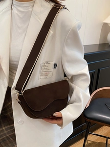 Dark brown saddle bag with a wide woven shoulder strap and matte vintage finish