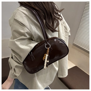 Detail of dark brown glossy underarm bag with wooden beads and fashion embossing