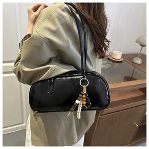 Detail of black glossy faux leather underarm bag with decorative wooden beads on strap