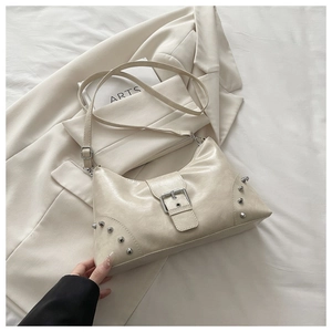 Macro view of cream shell bag featuring silver studs and metallic buckle closure detail