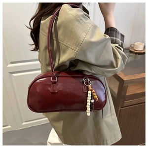 Chic burgundy cylindrical underarm bag with leather texture and stylish beaded tassel detail
