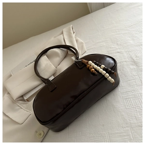 Detail of dark brown faux leather Boston bag with a unique wooden bead tassel accessory